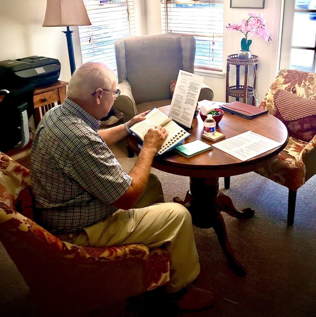 church member sitting at a round wooden table reading in the reading room